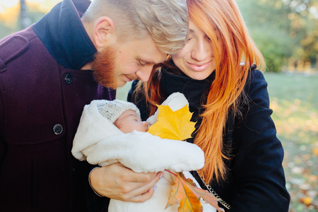 young family and newborn son posing for the camera in autumn parkの写真素材