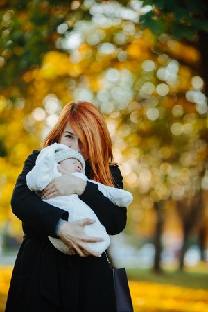 Mother and newborn son posing for the camera in autumn parkの写真素材