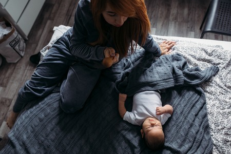 Portrait of a mother with her baby in bedroom at homeの写真素材