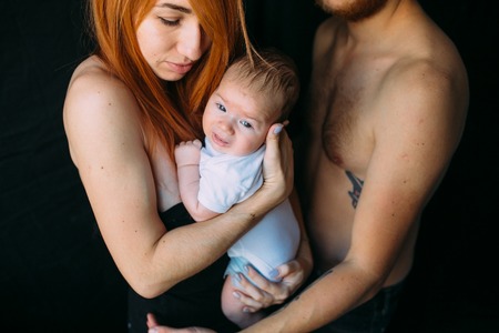 happy family on a black background holding a newborn baby in her arms.の写真素材