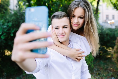 Beautiful young couple relaxing in the park and makes selfieの写真素材