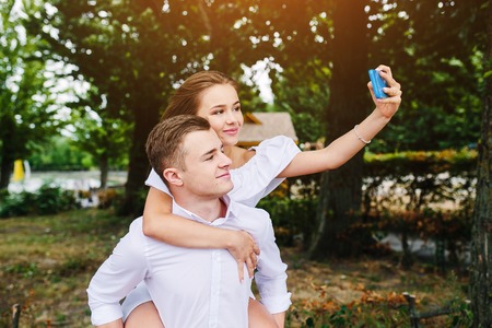 Beautiful young couple relaxing in the park and makes selfieの写真素材