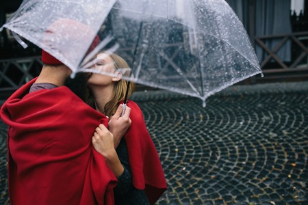 guy and the girl posing together in the rain on a city street