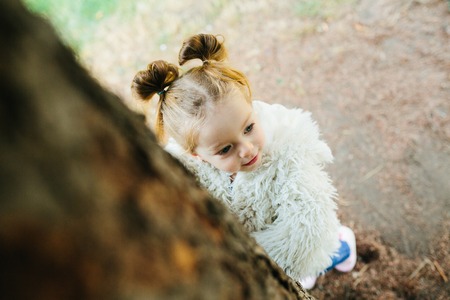 Cute little girl is playing hide and seek outdoorsの写真素材