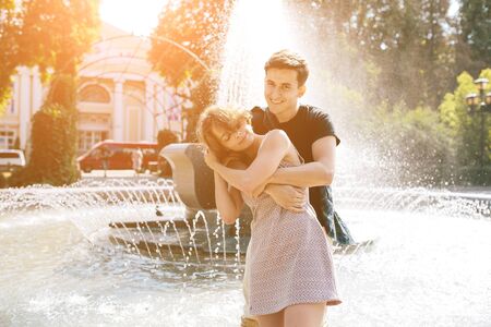 beautiful young couple at the fountain in the parkの写真素材