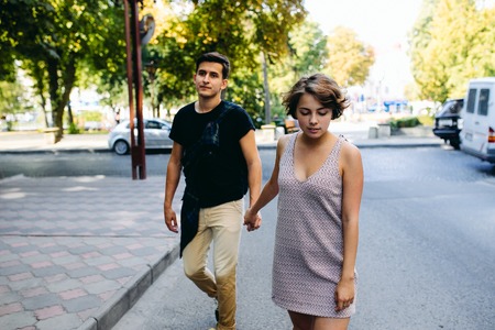 happy young couple of a handsome man and attractive woman walking on the street holding handsの写真素材