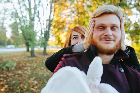 young family and newborn son posing for the camera in autumn park