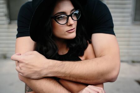 guy hugging his girlfriend from behind against a background of gray wall