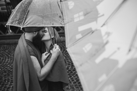 guy and the girl posing together in the rain on a city streetの写真素材