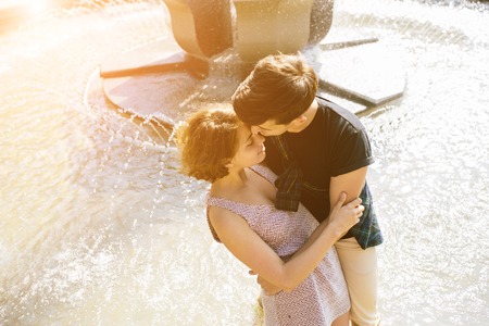 beautiful young couple at the fountain in the parkの写真素材