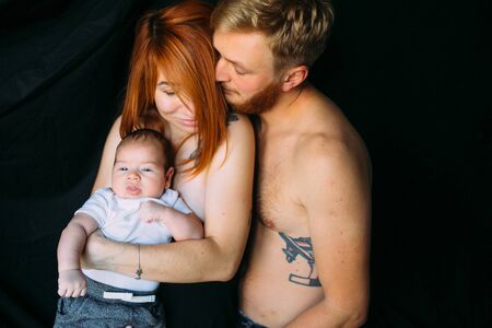 happy family on a black background holding a newborn baby in her arms.の写真素材