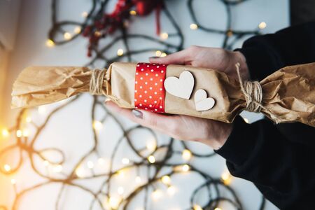 girl holding a Christmas gift in hand on the background of garlands