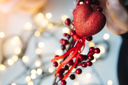 girl holding a red heart in the hands on the background of garlands