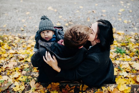 young family and newborn son posing for the camera in autumn parkの写真素材