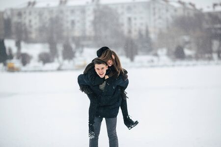 man carries his girlfriend on the back in the park, in winter holidaysの写真素材