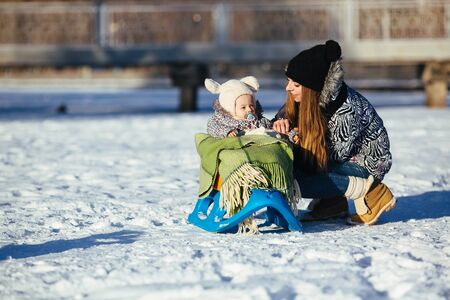 happy family mother and baby girl daughter playing and laughing in winter outdoors in the snowの写真素材