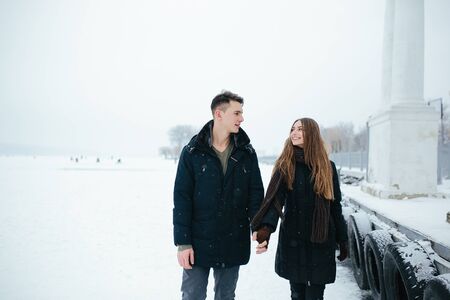 couple posing in a snowy park, in winter holidays