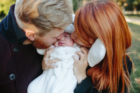 young family and newborn son posing for the camera in autumn parkの写真素材