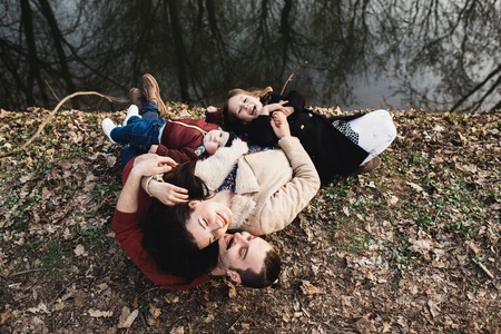 cheerful and friendly family resting on the river bank in the autumn park