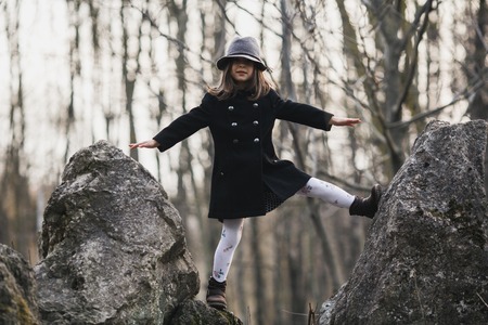 little girl in a black coat and hat posing in autumn parkの写真素材