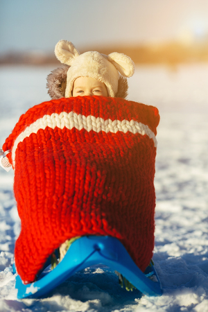 portrait of cute little girl child sitting on sledges at winter day with fresh snowの写真素材