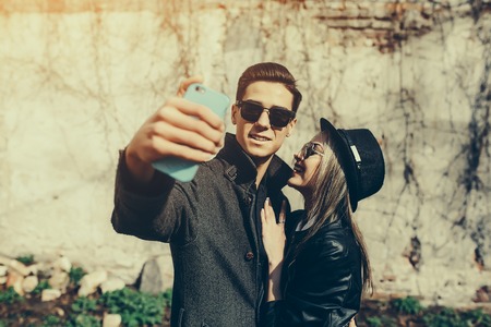 Photo of a young beautiful couple making selfie on wall backgroundの写真素材