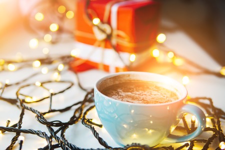 cup of coffee on the table, a garland in the backgroundの写真素材