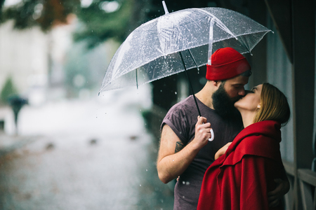 guy and the girl kissing under an umbrellaの写真素材