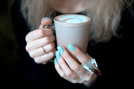 blonde woman holding a hot drink cupの写真素材