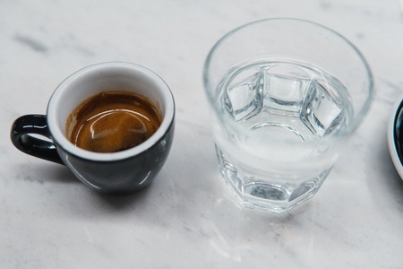 cup with coffee near a glass of waterの写真素材