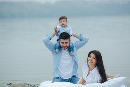 Happy young family relaxing together on the lakeの写真素材