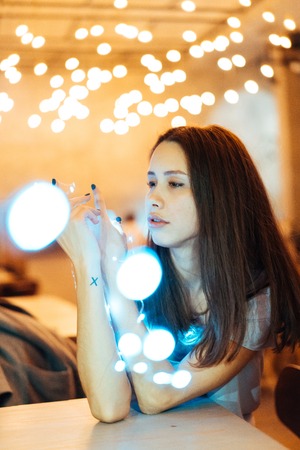 Woman holding glowing christmas garland in hands