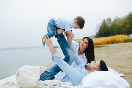 Happy young family relaxing together on the lakeの写真素材