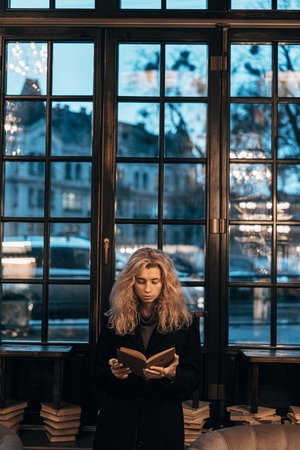Woman reading a book on the background of windowの写真素材