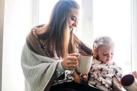 Mom and daughter drink something with mugの写真素材