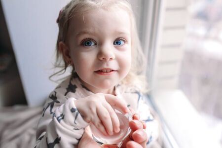 Little girl sitting near the windowの写真素材