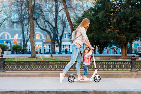 Mom and little daughter on a scooterの写真素材