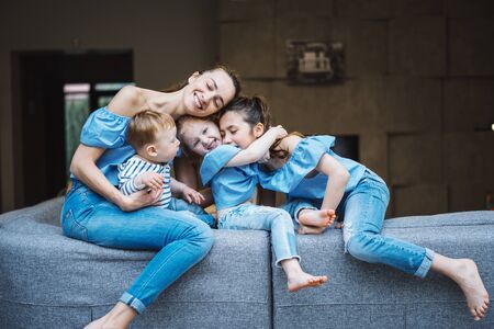 Mom, two daughters and a little son on the couchの写真素材