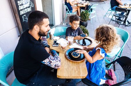 Dad, daughter and son are eating dessertの写真素材