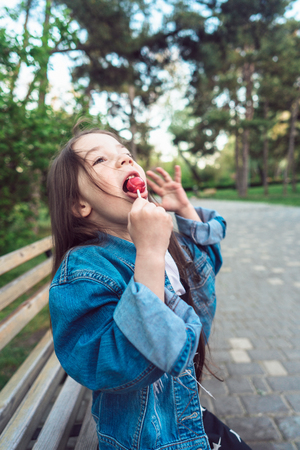 Girl sitting on bench with candiesの写真素材