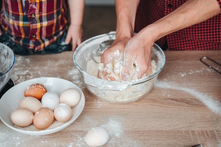 Dad and son make dough in the kitchen