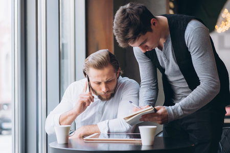 Two businessmen discussing work and using tabletの写真素材