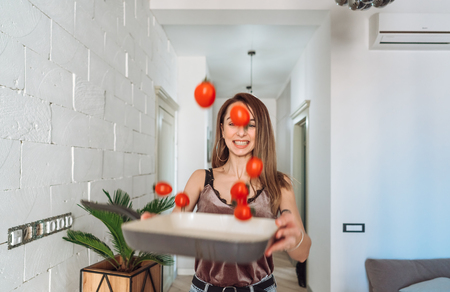 girl throws tomatoes on a trayの写真素材