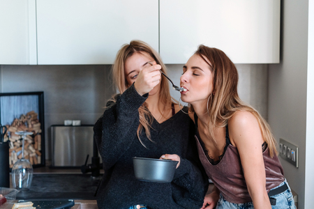 two girls eat porridge at home