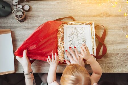 Woman wrapping present in paper with red ribbon.の写真素材