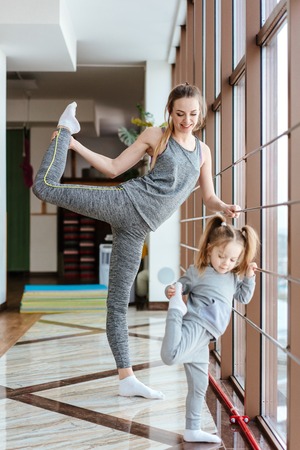 Mom and daughter together perform different exercisesの写真素材
