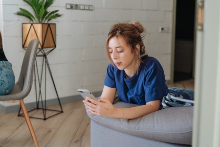 Pretty girl using her smartphone on couch at homeの写真素材