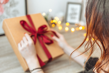 Woman wrapping present in paper with red ribbon.の写真素材
