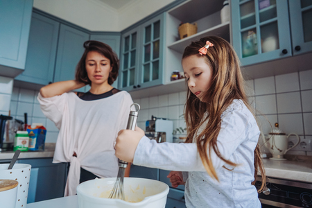 mom teaches her little daughter to cook foodの写真素材