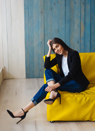 Young woman sitting on yellow sofaの写真素材